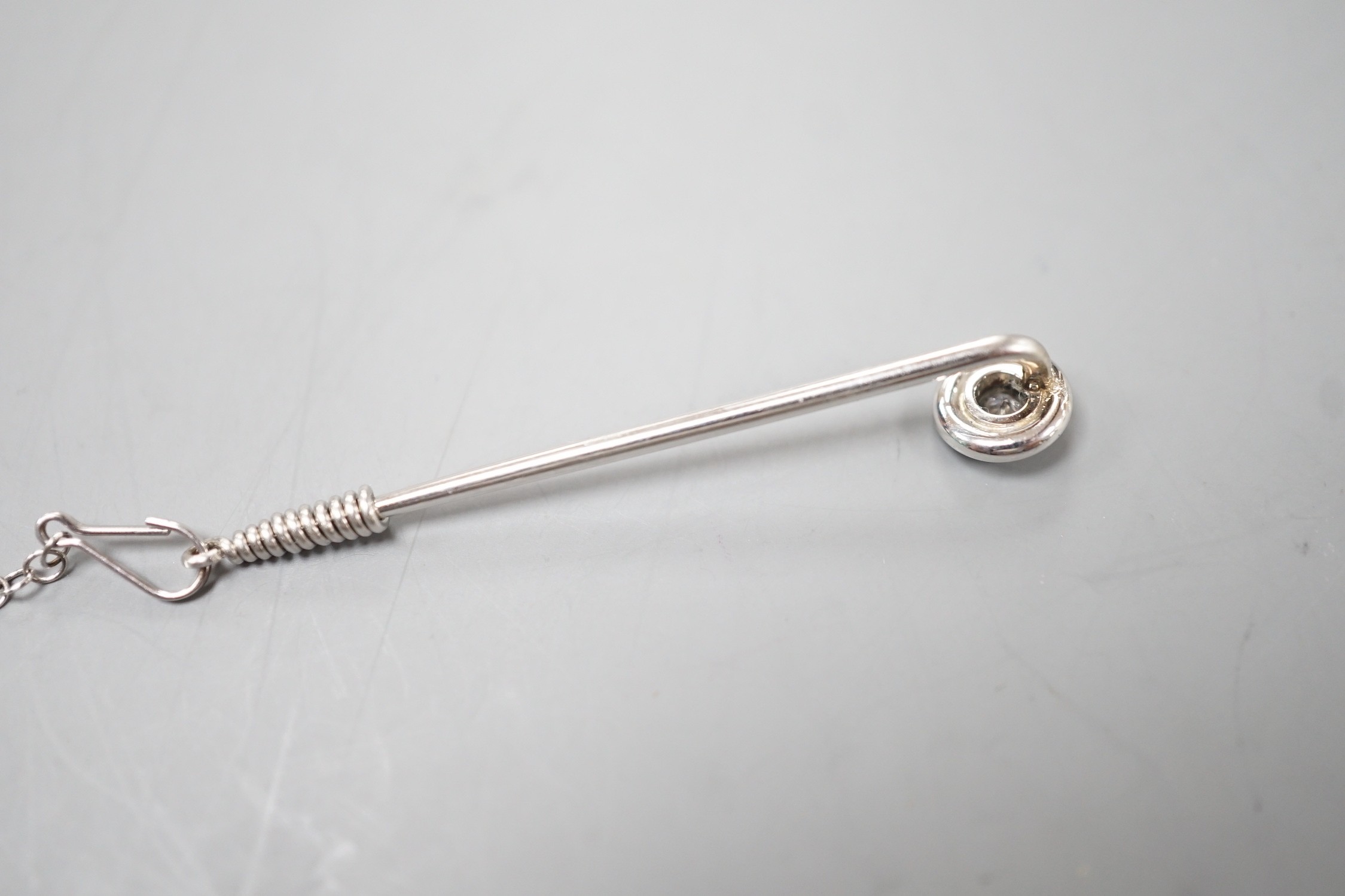 A white metal and collet set solitaire diamond tie pin, 43mm, with safety chain, gross weight 2.1 grams.